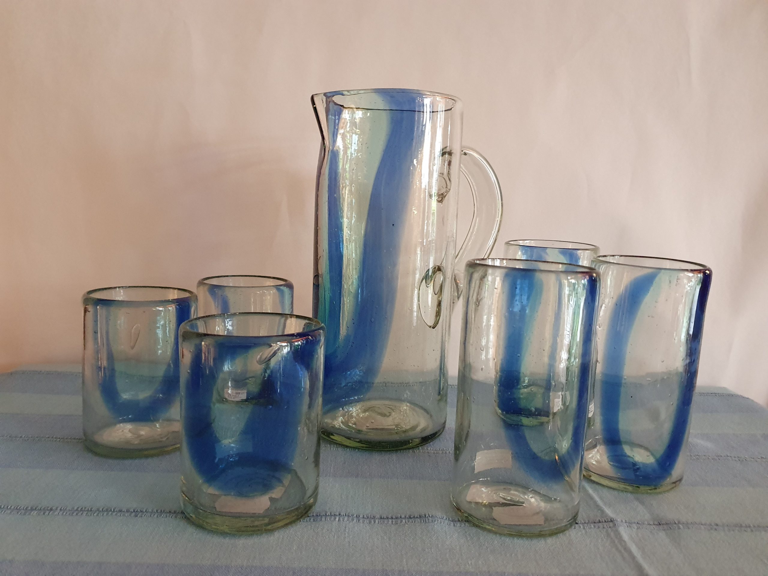 Das Bild zeigt einen Glaskrug und Gläser mit blauem Muster