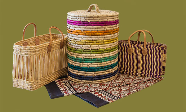 Geflochtene bunte Wäsche- und Einkaufsörbe und eine Überdecke auf grünem Hintergrund